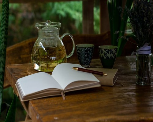 An open notebook and a cup of local herbal tea on a sunny table surface representing peaceful planning