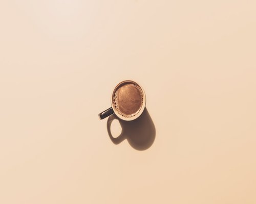 A classic white ceramic cup filled with fresh coffee on a clean neutral background